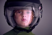 Entzückender kleiner Junge mit Motorradhelm und Blick in die Kamera. — Stockfoto