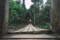 Handsome shirtless fit man walking on wooden bridge in the forest. — Stock Photo