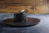 Seitenansicht von schwarzem Reis mit Tintenfischen auf schwarzem Teller — Stockfoto