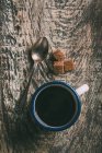 Прямо над видом на чашку кофе ложкой и коричневый сахар на деревенском деревянном столе — стоковое фото