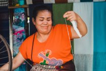 LAOS- FEBRERO 18, 2018: Mujer sonriente trabajando con tela - foto de stock