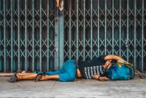 ЧАНГ-РАЙ, Таиланд - 12 февраля 2018 года: Бездомный лежит на сумке, как подушка на тротуаре — стоковое фото