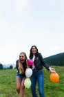 Laughing women throwing up balloons at nature — Stock Photo