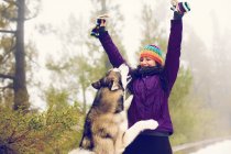 Riendo mujer jugando con perro en las nieves - foto de stock