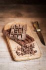 Barres et copeaux de chocolat sur planche à découper en bois — Photo de stock