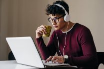 Молодий чоловік в навушниках друкує на ноутбуці вдома — стокове фото
