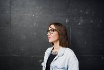 Brunette femme en lunettes posant sur gris — Photo de stock