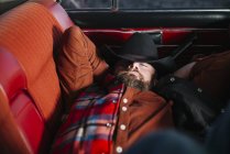 Чоловік в капелюсі і картата сорочка спить в старовинному автомобілі — стокове фото