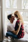 Giovane coppia sensuale che abbraccia alla finestra — Foto stock