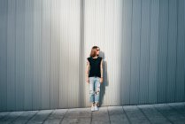 Stylish woman with tattoos standing on street at metallic wall. — Stock Photo