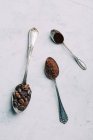 Directly above view of coffee beans and black coffee in retro spoons — Stock Photo