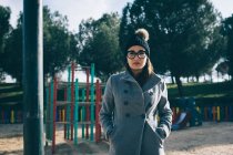 Woman in stylish warm clothes and looking at camera on playground. — Stock Photo