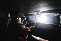 Bearded man in hat driving car at night. — Stock Photo