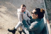 Niedliche Kleinkind auf Mutter Hände Blick in Kamera im Park — Stockfoto