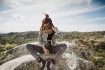 Молода жінка сидить на скелі і дивиться вниз — стокове фото
