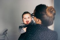 Adorable boy on mother hands looking at camera — Stock Photo
