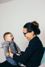 Side view of adorable boy on mother hands at home — Stock Photo