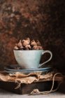Pile of chocolate truffles in cup against wooden box — Stock Photo