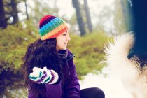 Laughing woman looking at dog in snow woods — Stock Photo