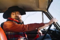 Bearded man in hat driving vintage car in sunny day — Stock Photo