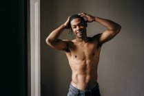 Shirtless black man posing at window and looking at camera — Stock Photo