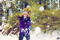 Sorrindo mulher jogando bolas de neve na floresta — Fotografia de Stock