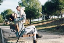 Веселий жінка, сидячи на клумби і Холдинг малюка у повітрі — стокове фото