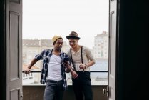 Amis multiethniques posant avec smartphone sur le balcon — Photo de stock