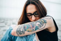 Чуттєва жінка з татуюваннями сидить на тротуарі — стокове фото
