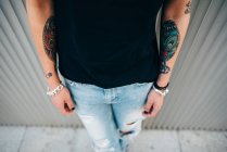 Crop stylish woman with tattooes at metal wall — Stock Photo