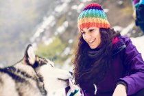 Smiling woman playing with dog in snows — Stock Photo