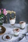 Stillleben süßer Desserts in Gläsern auf dem Tisch mit Bouquet — Stockfoto