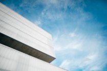 From below corner of modern concrete building against blue sky — Stock Photo