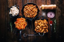 Организация вкусных блюд в сковородках на деревянном столе — стоковое фото
