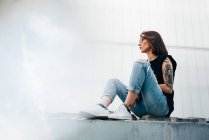 Vista lateral da mulher tatuada sentada no pavimento — Fotografia de Stock