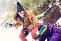 Happy friends playing snowballs in woods — Stock Photo