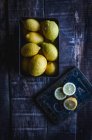Сверху свежие целые и нарезанные лимоны на деревянном столе . — стоковое фото