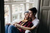 Gelassenes junges Paar umarmt sich auf Fensterbank — Stockfoto