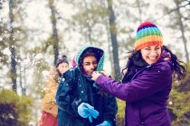 Donne allegre nascondendo il viso dalle palle di neve nei boschi — Foto stock
