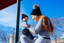 Side view of young mother playing with cute toddler at park — Stock Photo
