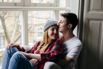 Tender couple hugging on window sill with eyes closed — Stock Photo