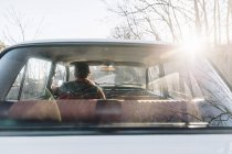 Vue arrière de l'homme conduisant une voiture blanche vintage dans la nature . — Photo de stock