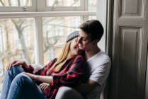 Giovane coppia sensuale che si abbraccia sul davanzale della finestra a casa — Foto stock
