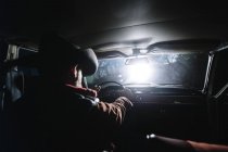 Rückansicht eines Mannes mit Hut, der nachts Auto fährt — Stockfoto
