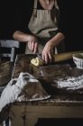 Midsection of woman cutting dough roll on table — Stock Photo