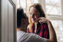 Парень чувственно трогает лицо девушки за окном дома — стоковое фото