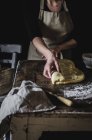 Кукурудзяна жінка розкачує тісто, готуючи солодке тісто на кухонному столі . — стокове фото