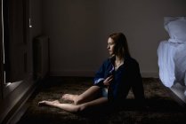 Вид збоку на безтурботну жінку позує на підлозі в кімнаті — стокове фото