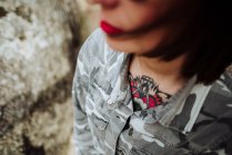 Татуированная женщина в очках, позирующая перед камнями — стоковое фото