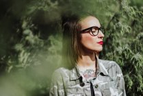 Стильна татуйована жінка в окулярах позує на природі — стокове фото